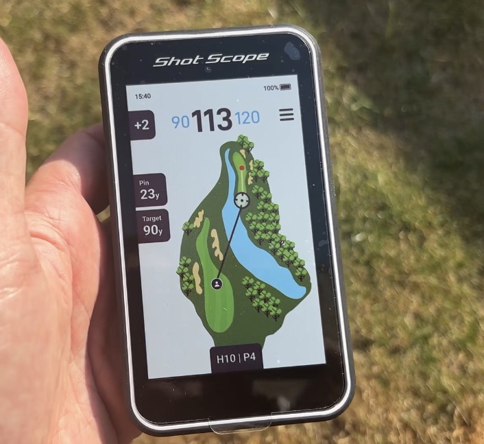 Shot Scope H50 handheld golf GPS being used on a golf course showing a full-colour hole map and yardages