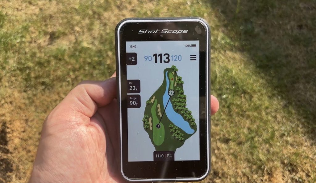Shot Scope H50 handheld golf GPS being used on a golf course showing a full-colour hole map and yardages
