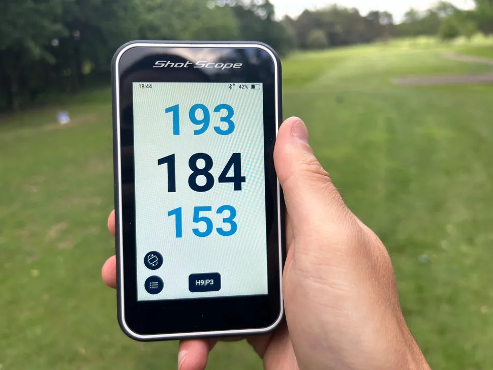 Shot Scope H50 handheld golf GPS being used on a golf course showing a full-colour hole map and yardages